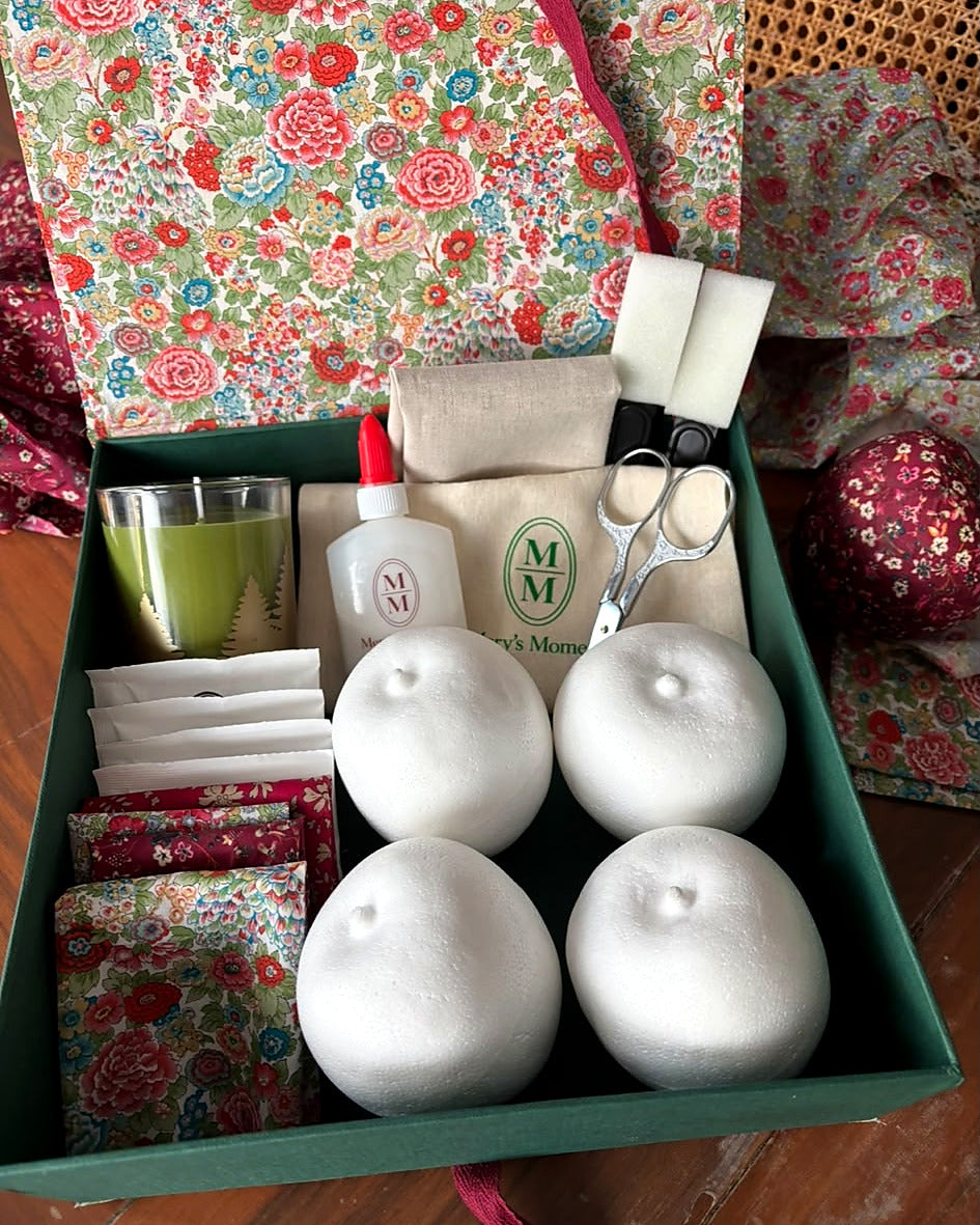 Interior del kit Mery's Moment con cuatro bases de manzana, telas Liberty, cola, tijeras, esponjas y vela