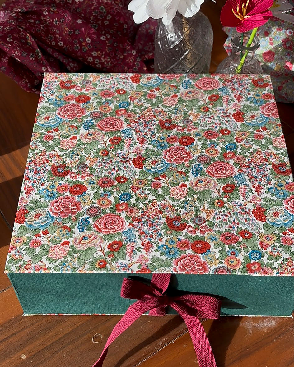 Packaging del kit Manzanas de Navidad Liberty: caja floral con base verde y lazo burdeos