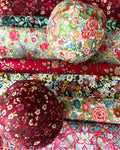 Dos manzanas decorativas de Navidad terminadas con telas Liberty florales, una burdeos y otra multicolor
