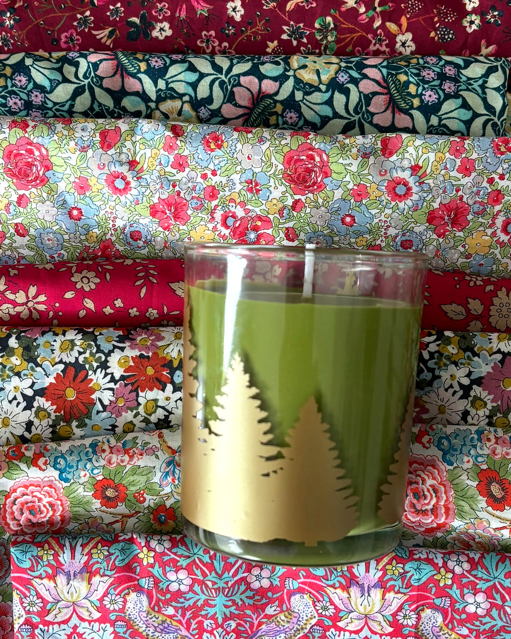 Vela navideña verde con siluetas doradas de abetos, incluida en el kit Mery's Moment